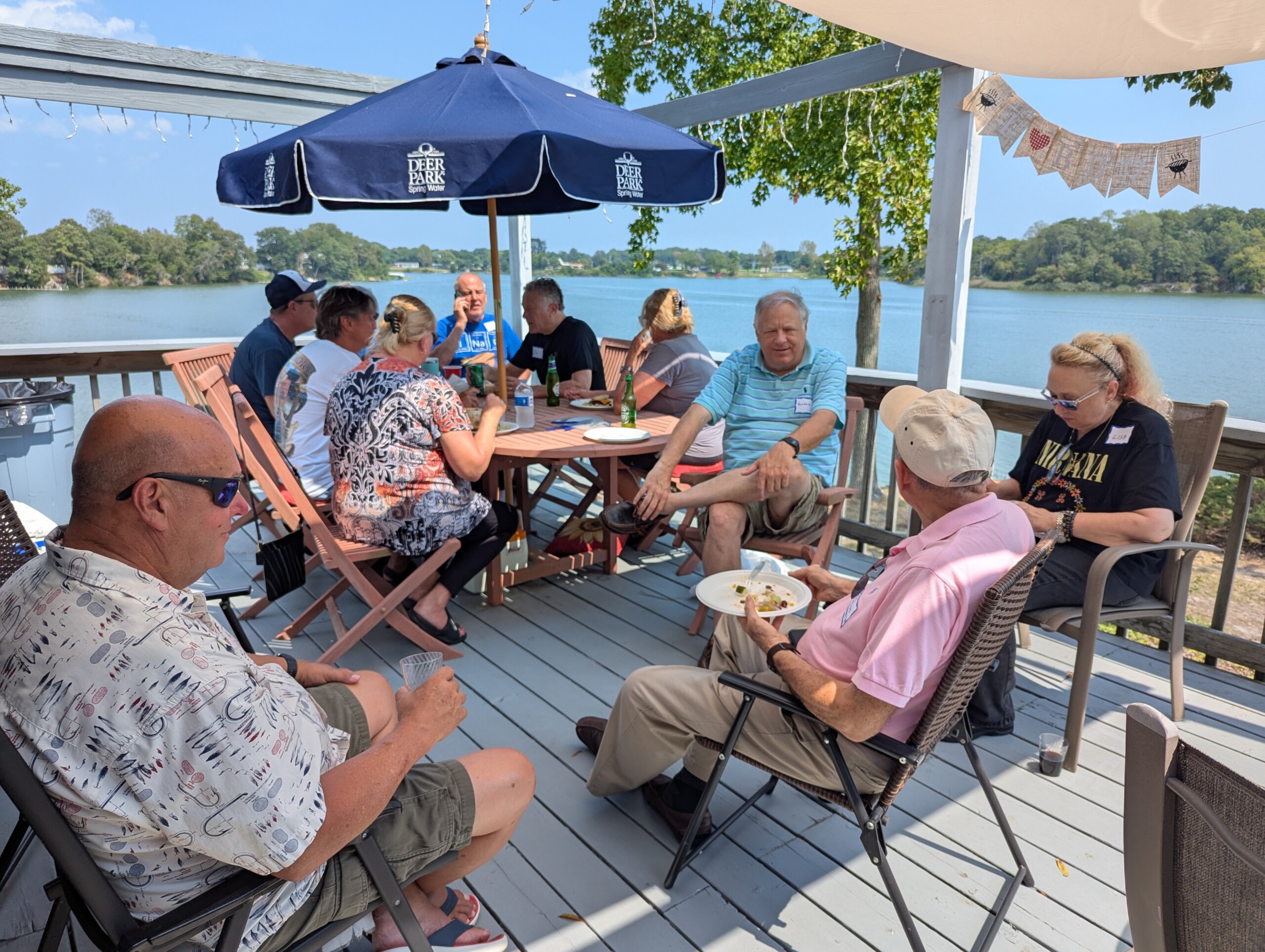 People enjoying outdoor gathering on lakeside deck.